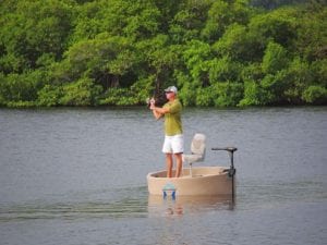 A guy casting a fishing rod from a tan round boat