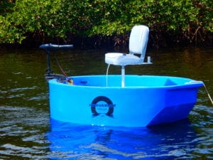 A blue round boat sitting on white sand in the shade