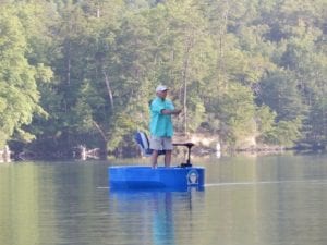 A fisherman casting his line from a blue round boat